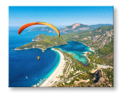Slika na platnu s motivom paraglajding iznad plave lagune i plaže obješena u modernom stilskom interijeru iznad drvene konzole s vazom i svijećom, Papilora.