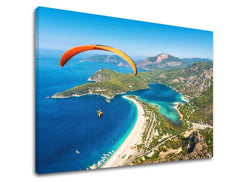 Slika na platnu s motivom paraglajding iznad plave lagune i plaže – 3D prikaz platna s vidljivim drvenim okvirom, Papilora.
